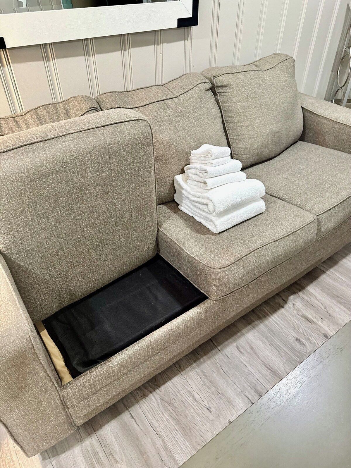 Ein beiges Sofa mit einem schwarzen Tablett und einem Stapel weißer Handtücher.