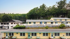 A motel with a row of rooms, each with a front porch and a small table.