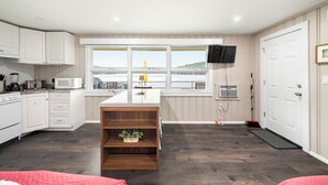 A modern kitchen with white cabinetry, a central island, and a large window overlooking a scenic view.
