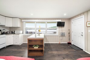 A modern kitchen with white cabinetry, a central island, and a large window overlooking a scenic view.