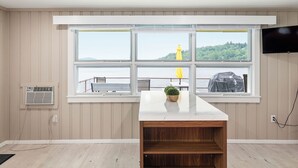 A room with a large window, a flat-screen TV, and a wooden shelf.