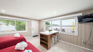 A hotel room with a bed, a small kitchen area, a seating area with a view, and a television mounted on the wall.