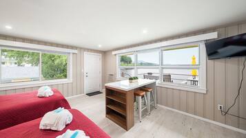 A hotel room with a bed, a small kitchen area, a seating area with a view, and a television mounted on the wall.