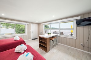 A hotel room with a bed, a small kitchen area, a seating area with a view, and a television mounted on the wall.