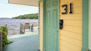 A green door with the number 31, a mailbox, and a bench overlooking a body of water.