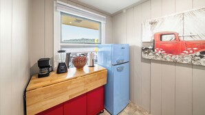 A compact kitchen with a wooden counter, a blue refrigerator, and a window with a view of the outdoors.