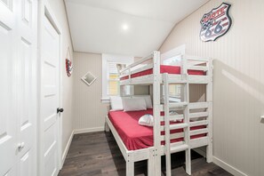 A bunk bed room with white walls, a window with blinds, and a door with a handle.