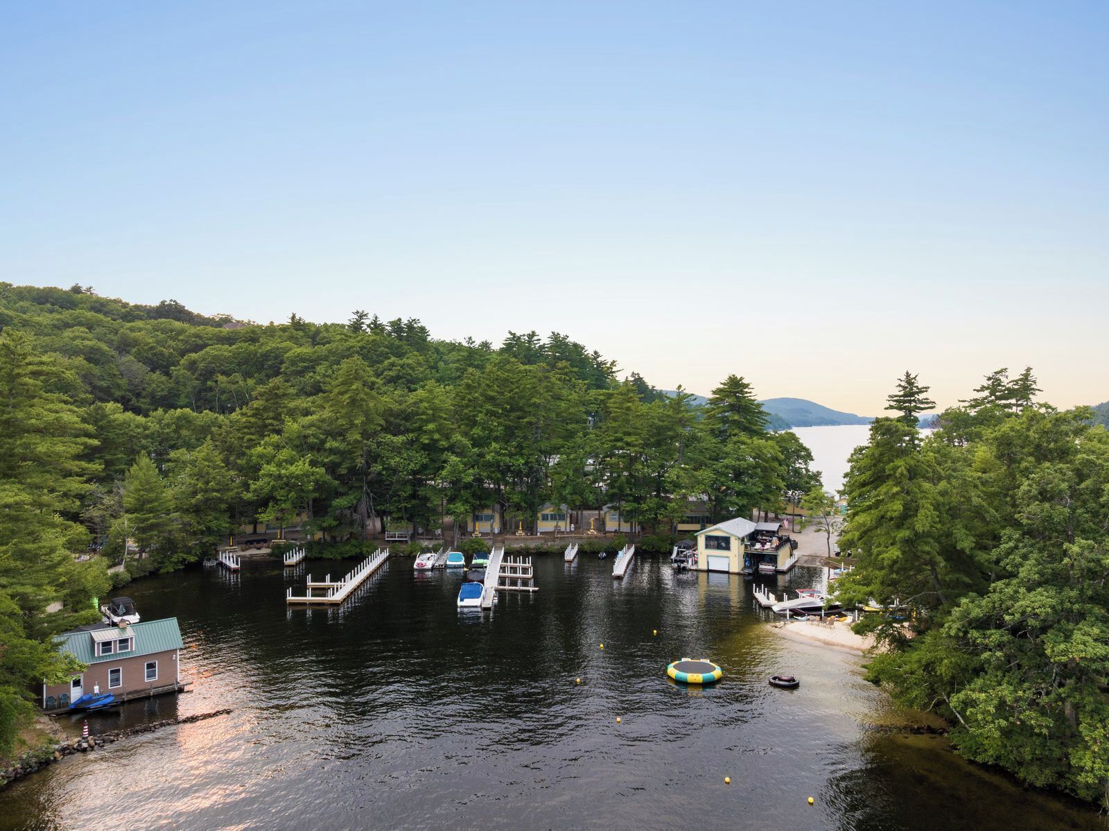 A riverside dock with boats, a small house, and dense forest.