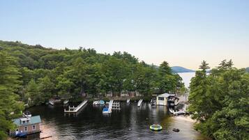 A riverside dock with boats, a small house, and dense forest.