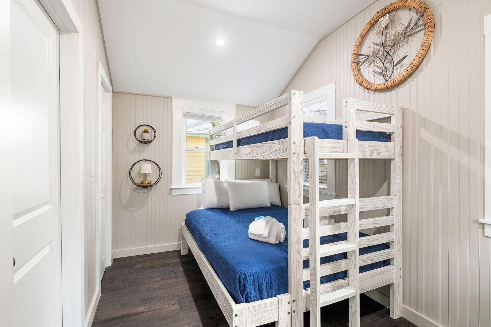 A room with bunk beds, a window, and a wall-mounted decorative item.