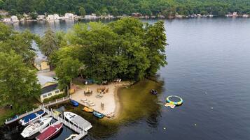 A lakeside property with a dock, boats, and a sandy beach area.