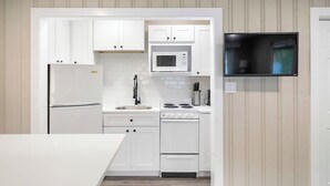 A modern kitchen with white cabinetry, a microwave, a stove, and a sink.