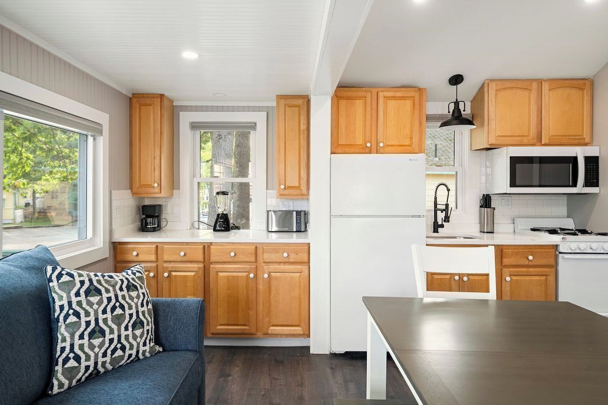 A modern kitchen with wooden cabinets, a refrigerator, microwave, and a stove.