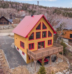 A two-story wooden house with a red roof and a balcony. - Cardinal chalet (Saint-Philémon)