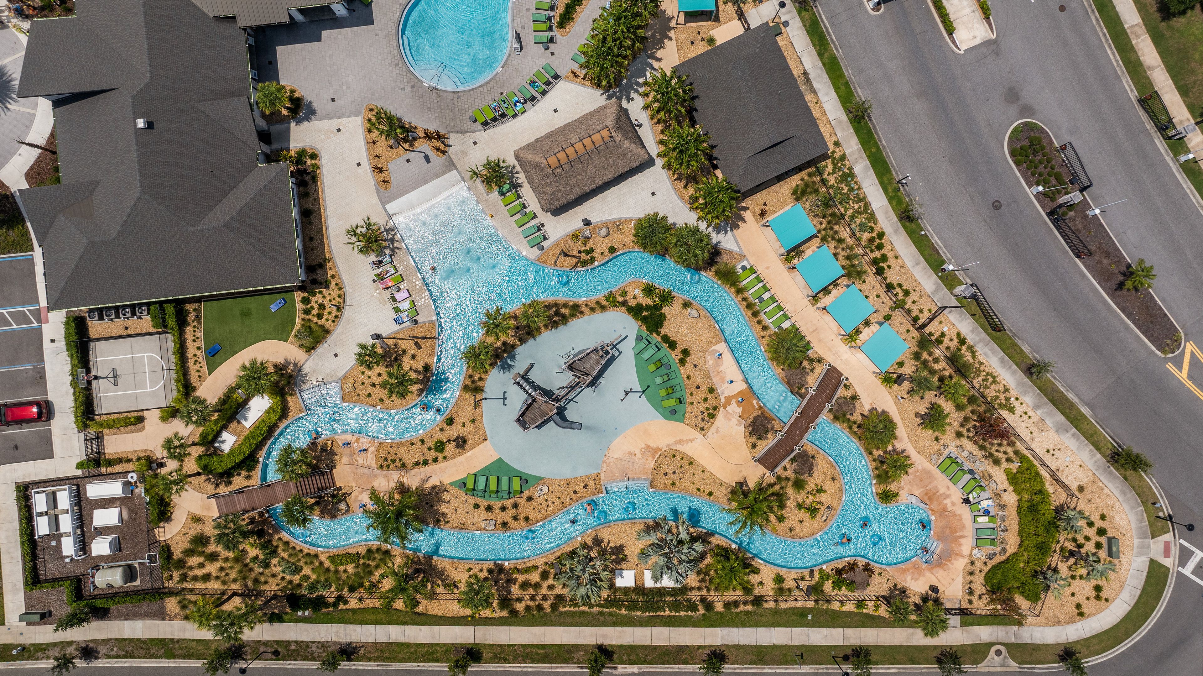 Vista aérea de un resort con una piscina serpenteante, un elemento acuático central y varias zonas de descanso.