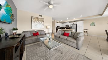 A modern living room with a sofa, coffee table, and a TV mounted on the wall.