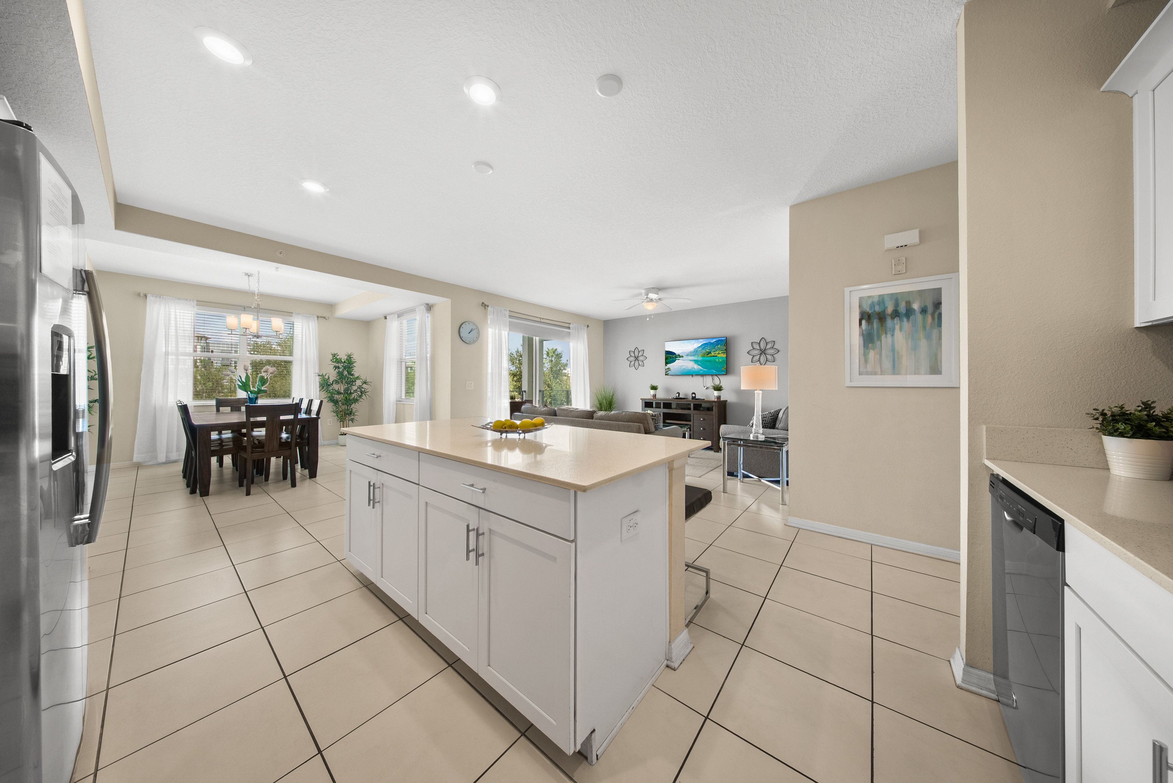 A modern kitchen with a central island, dining area, and a living space with a view.