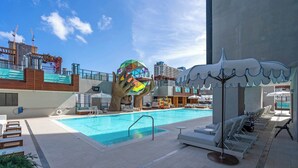 Une piscine avec des chaises longues et une grande sculpture.