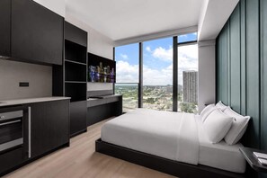 A modern hotel room with a large bed, a built-in desk, and a city view. - Highrise Condo & Amenities for 2 people (Miami)