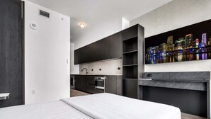 Une chambre d’hôtel moderne dotée d’un lit, d’une cuisine intégrée et offrant une vue sur la ville.