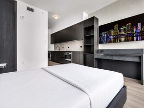 A modern hotel room with a bed, a built-in kitchen, and a cityscape view. - Highrise Condo & Amenities for 2 people (Miami)