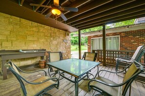 Un patio exterior con una mesa, sillas, un ventilador de techo y una pared de ladrillo.