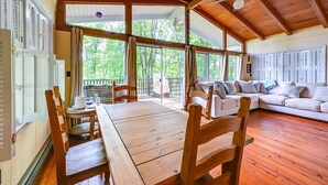 A spacious room with a wooden ceiling, large windows, a wooden table, and a sofa. - Waterfront Nolin Lake Retreat: Lake Views (Ollie)
