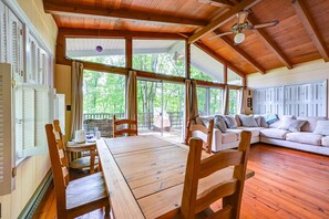 A spacious room with a wooden ceiling, large windows, a wooden table, and a sofa. - Waterfront Nolin Lake Retreat: Lake Views (Ollie)