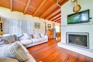 A cozy living room with a fireplace, wooden floors, a sofa, and a television.