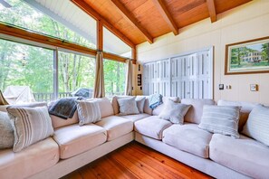 A cozy room with a large window, a wooden ceiling, and a beige sofa with multiple cushions. - Waterfront Nolin Lake Retreat: Lake Views (Ollie)