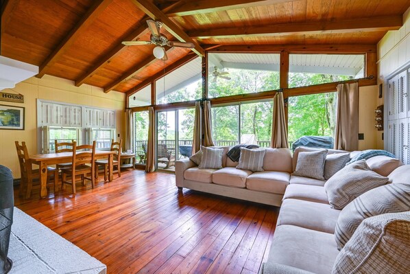Una habitación amplia con piso de madera, un sofá grande y una mesa de comedor con sillas.