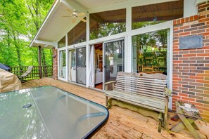 A covered outdoor area with a glass enclosure, a wooden deck, and a brick wall. - Waterfront Nolin Lake Retreat: Lake Views (Ollie)
