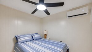A bedroom with a bed, a ceiling fan, an air conditioning unit, and a bedside table with a lamp. - Waterfront Nolin Lake Retreat: Lake Views (Ollie)