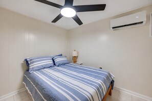 A bedroom with a bed, a ceiling fan, an air conditioning unit, and a bedside table with a lamp. - Waterfront Nolin Lake Retreat: Lake Views (Ollie)