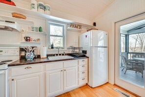 A kitchen with white cabinets, a white refrigerator, a window with a view, and a 'PEACE' sign above the window. - Waterfront Nolin Lake Retreat: Lake Views (Ollie)