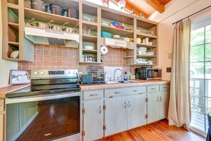 A kitchen with a built-in oven, microwave, and a variety of cookware and dishes.