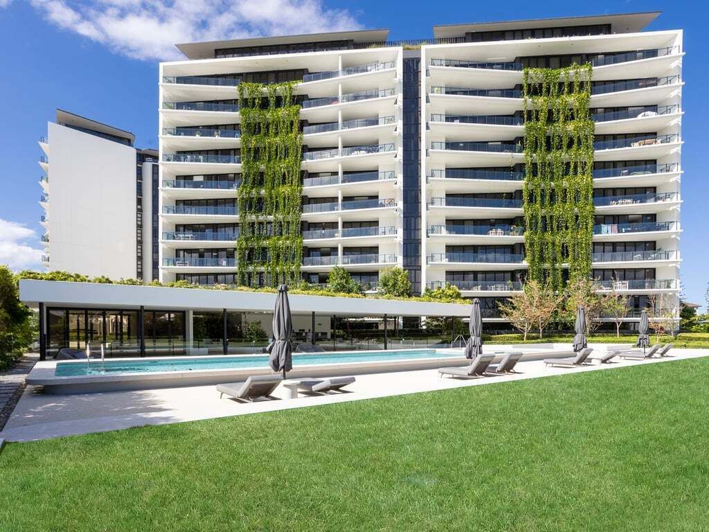 A modern apartment building with a rooftop pool and outdoor seating area.