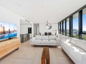 Ein modernes Wohnzimmer mit einer Couch, einem Couchtisch und einem Fernseher auf einer Holzkommode.