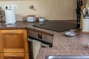 A kitchen with a granite countertop, stainless steel appliances, and wooden cabinets. - Phenomenal 3-bedroom house in Santo António With fantastic view and hiking trail (Santo António)