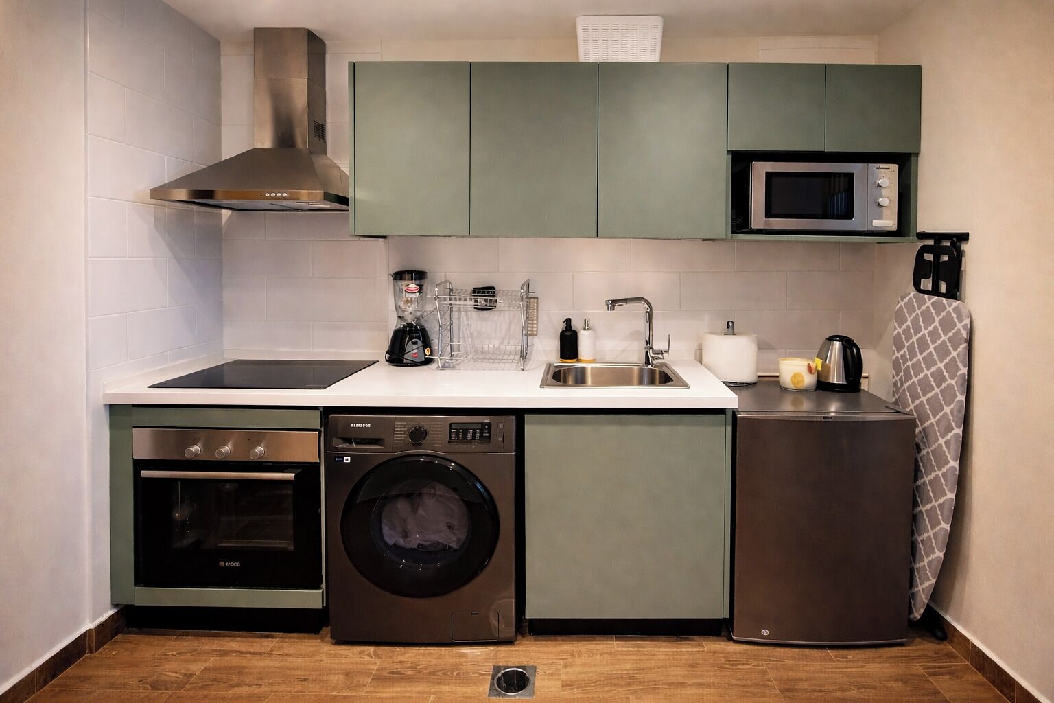 Een compacte keuken met een inbouwoven, magnetron en wasmachine.