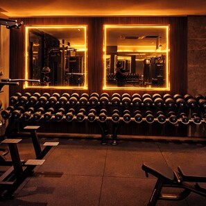 Ein Fitnessraum mit Spiegelwand, Kurzhanteln und Trainingsgeräten.