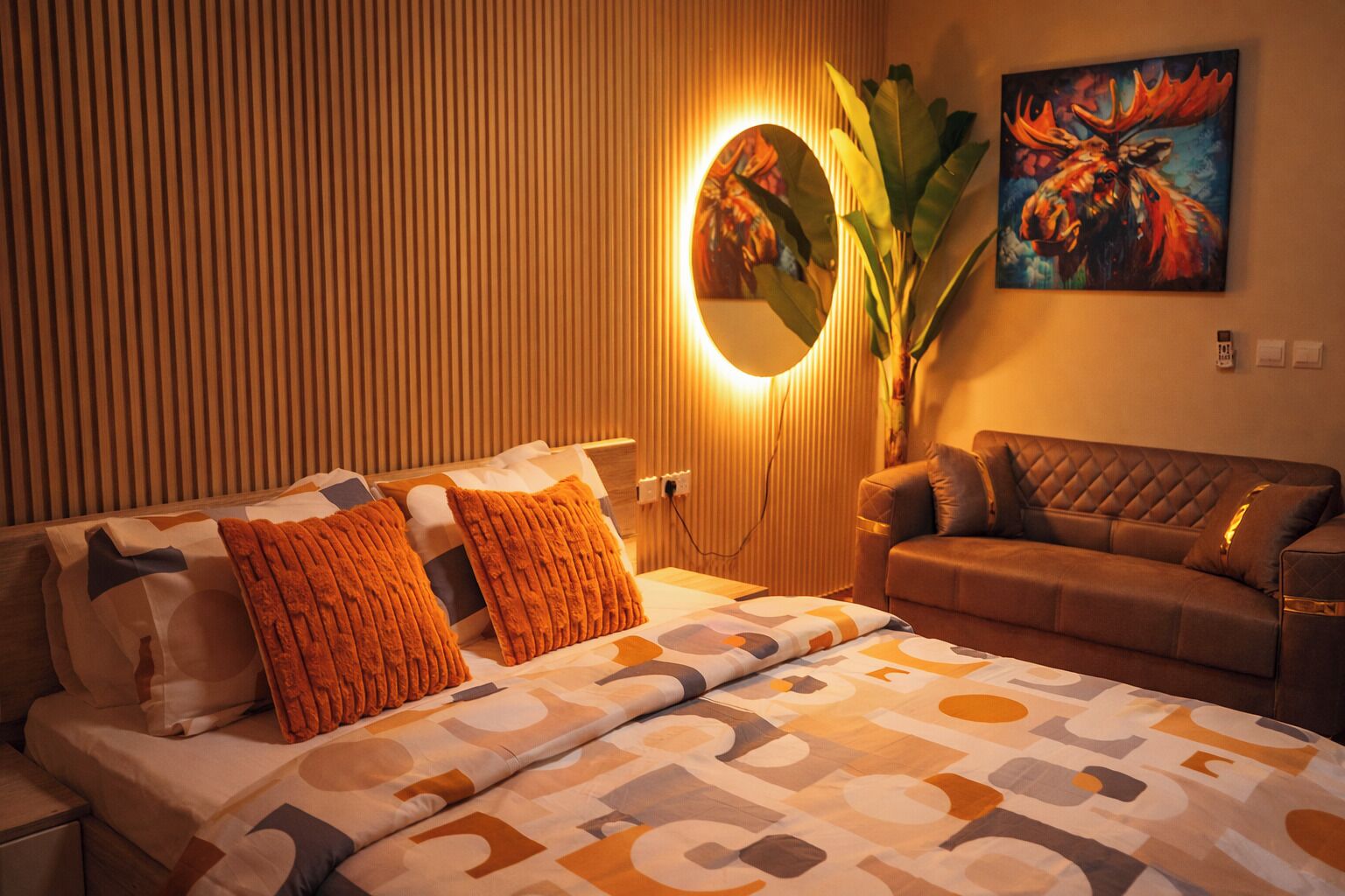 Een hotelkamer met een bed, een bank, een spiegel aan de muur en een schilderij.