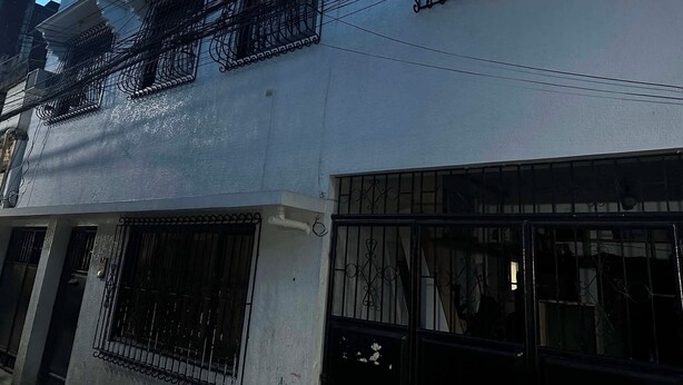 A multi-story building with balconies, a gated entrance, and a window with a metal grill.
