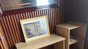 A small wooden desk with a framed motivational quote, a white chair, and a slanted shelf.