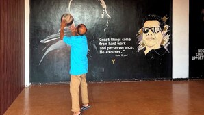 A basketball court with a Spalding basketball hoop, a mural with a basketball player, and a quote by Kobe Bryant.
