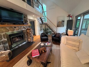Ein geräumiges Wohnzimmer mit Kamin, Treppe, Sofa und Couchtisch.
