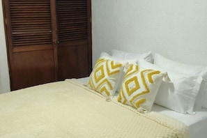 Un lit avec une couvre-lit blanche et deux oreillers à motifs géométriques.
