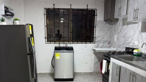A kitchen with a refrigerator, water heater, stove, and cabinets. - Family-Friendly 3-Bedroom Apartment Near San Felipe Castle (cartagena)