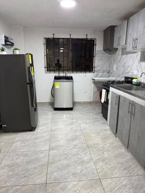A kitchen with a refrigerator, water heater, stove, and cabinets. - Family-Friendly 3-Bedroom Apartment Near San Felipe Castle (cartagena)