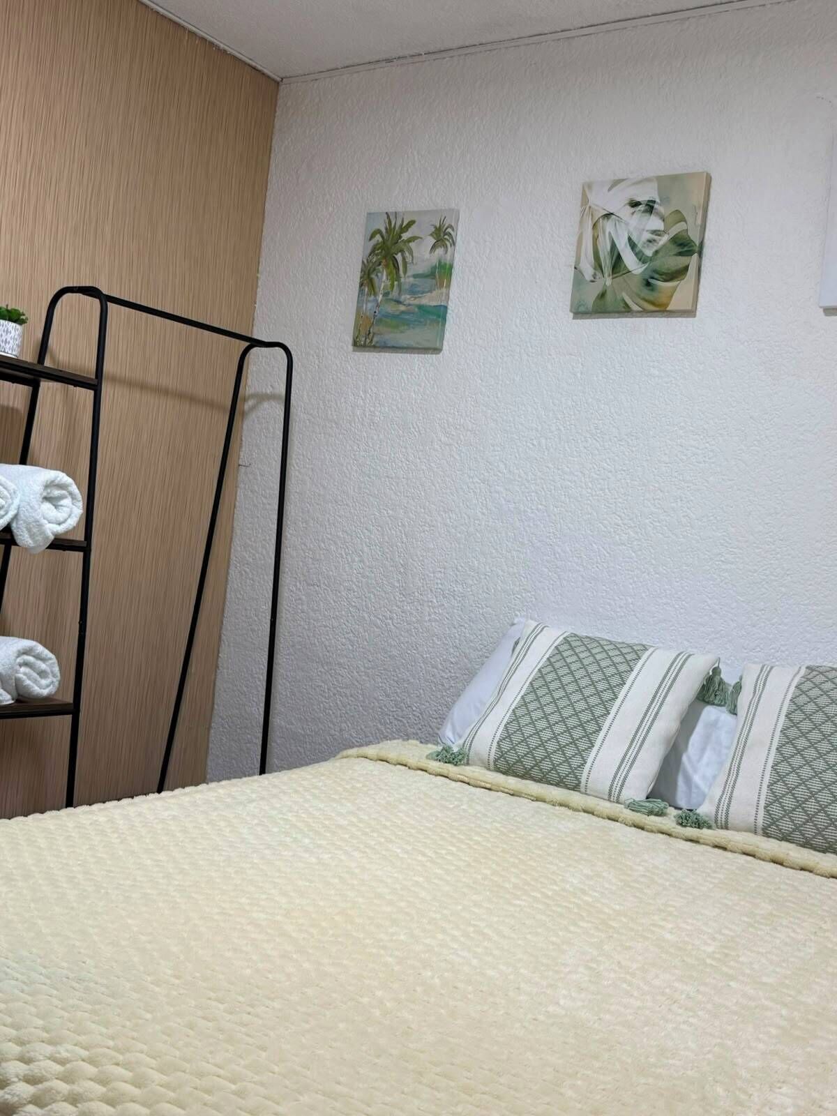 Une chambre avec un lit superposé, une étagère avec des serviettes et deux œuvres d’art murales.